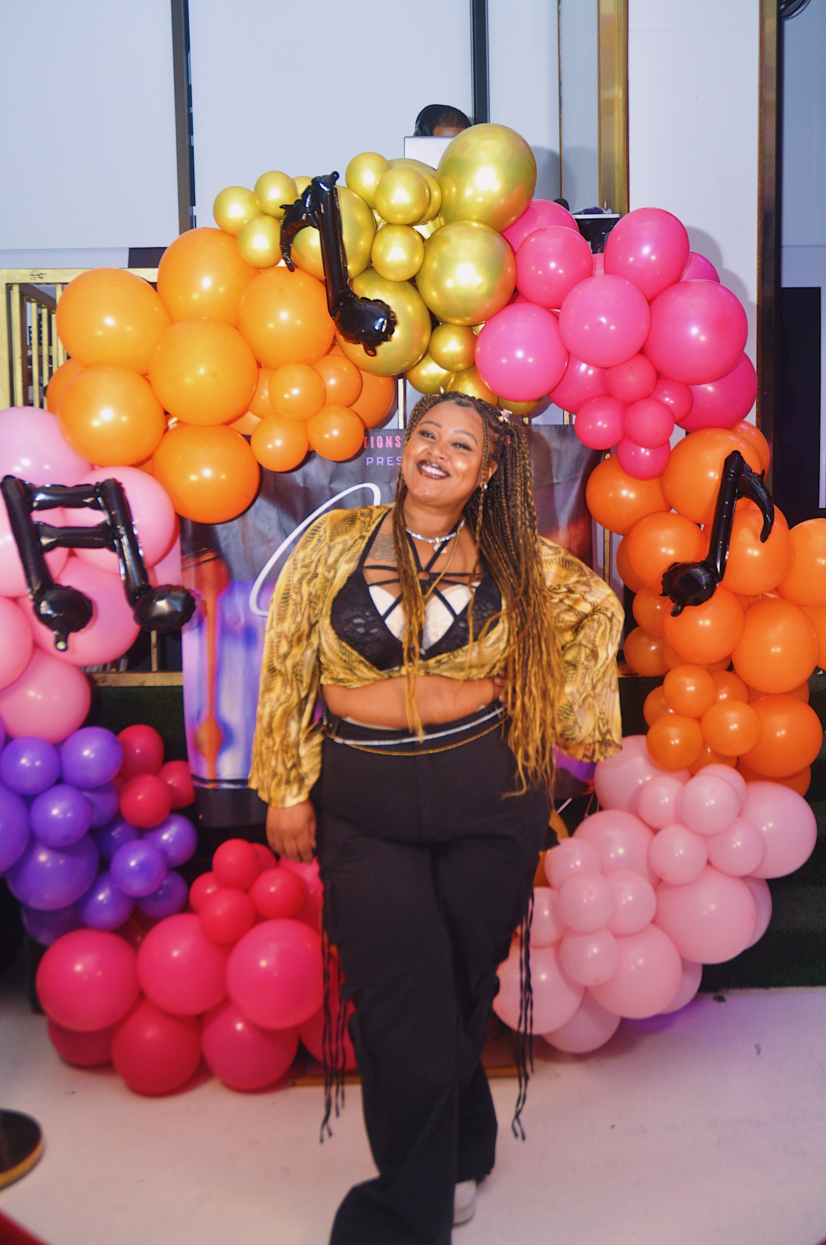 Golden562 posing in front of a colorful balloon arch with musical notes.